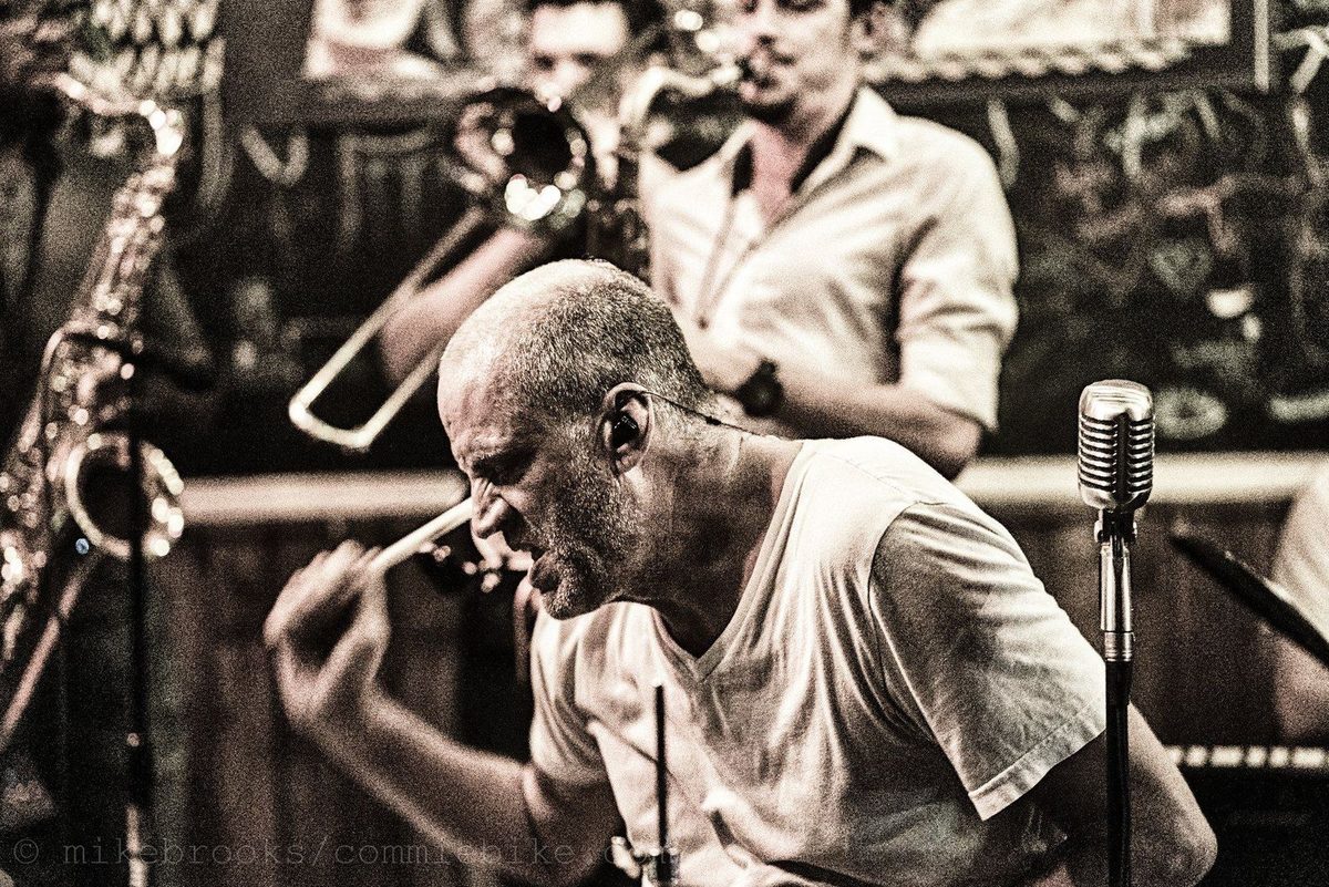 John Jay Myers drumming with the horn section behind him