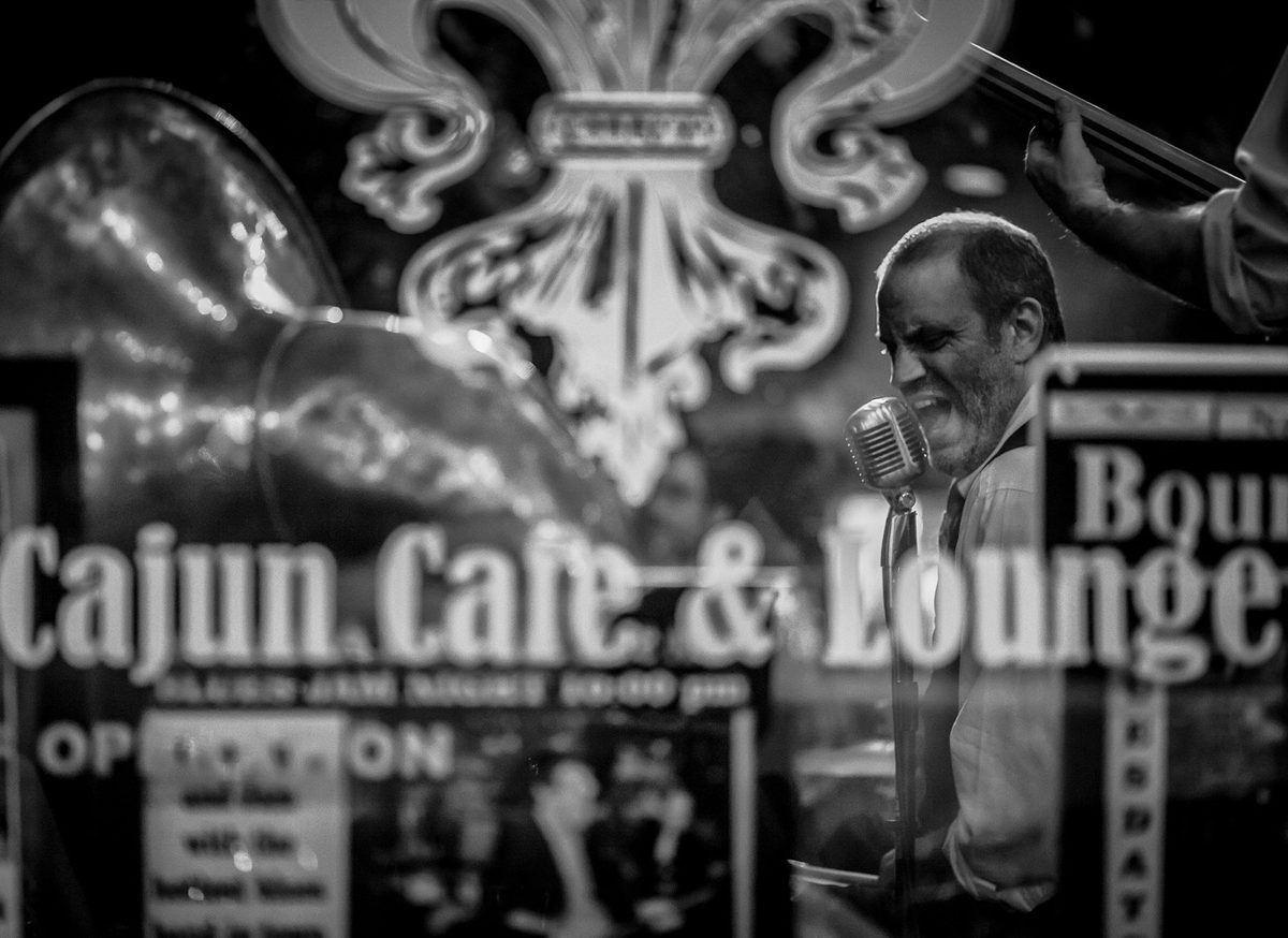 John Jay Myers singing, seen through the window of The Free Man Cajun Cafe & Lounge