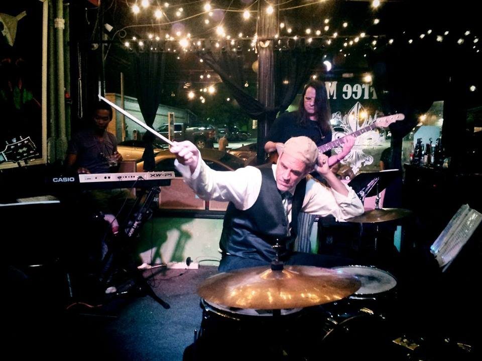 John Jay Myers drumming under string lights